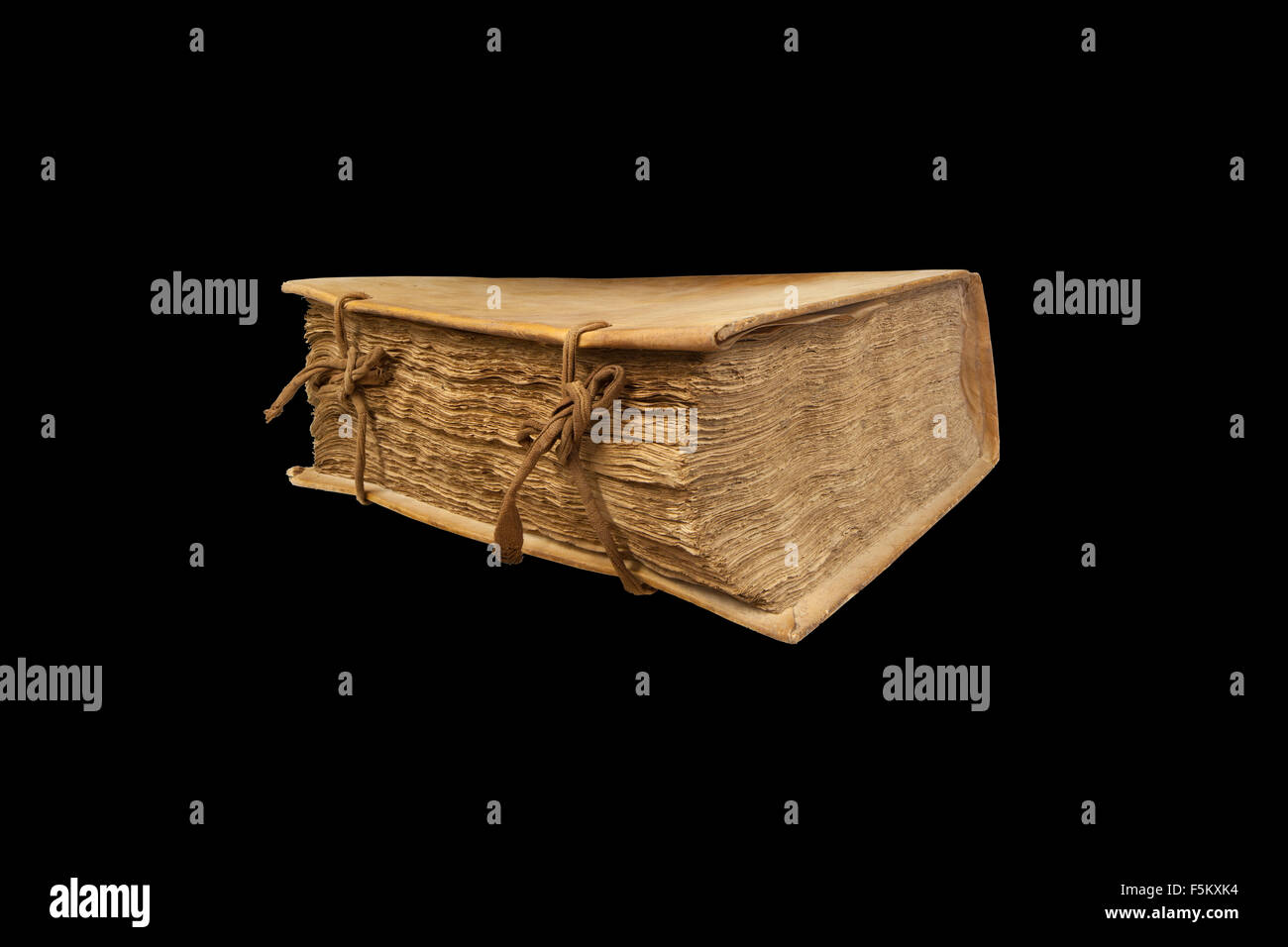 Ancient book. Clipping path. Side view. Closed book with streaks of fabric. Black background. Stock Photo