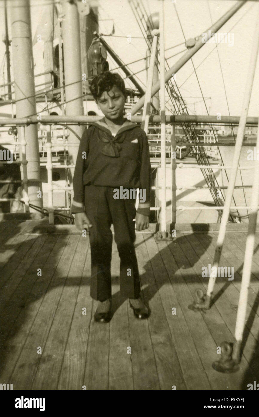 Child dressed as a sailor on the deck of a ship, Italy Stock Photo