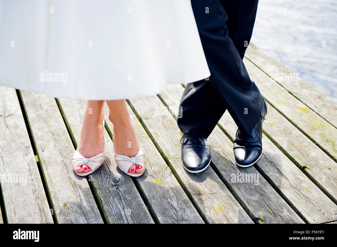 Sweden, Uppland, Arholma, Feet of man and woman standing on wooden pier Stock Photo