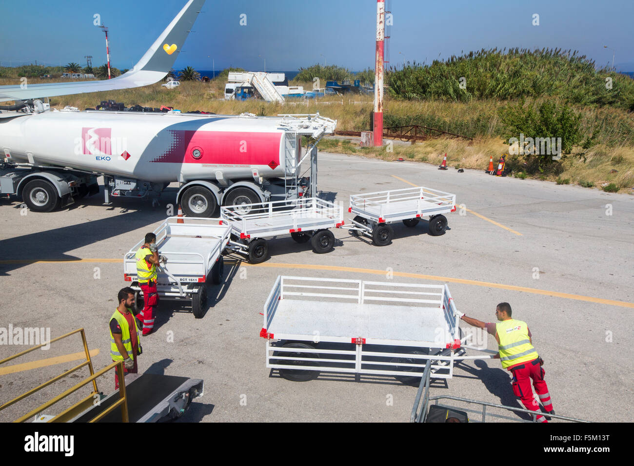 Baggage handlers and a refuelling tanker at Mytilene airport on Lesvos, Greece. Stock Photo