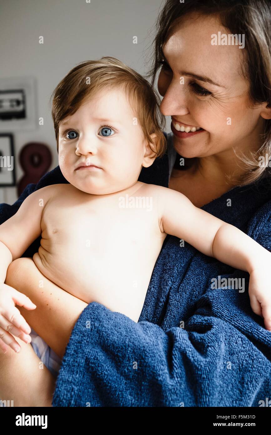 Mother holding baby son, looking away Stock Photo