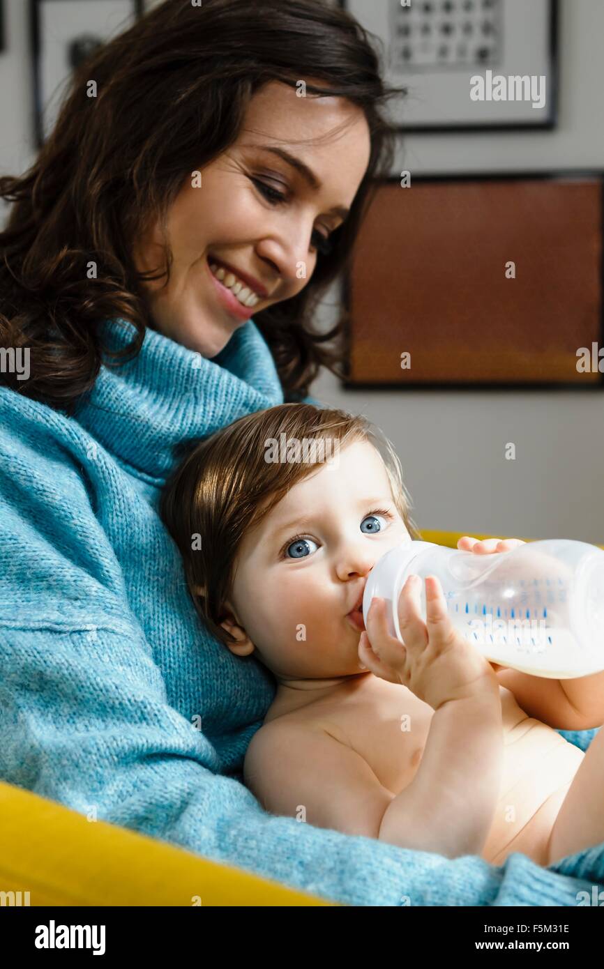 Mother holding baby son whilst he drinks from bottle Stock Photo