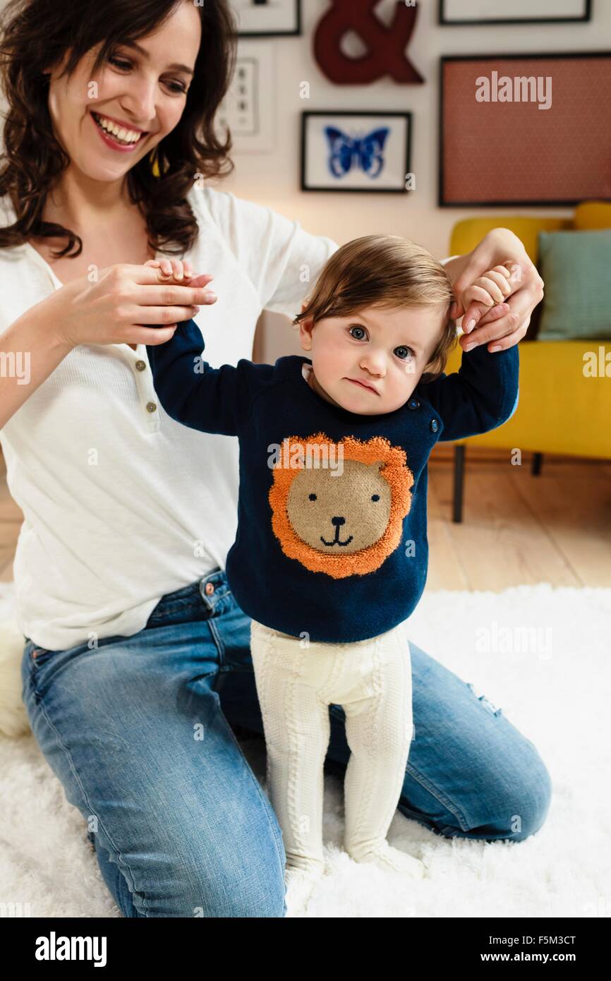 Mother helping her baby son to stand Stock Photo
