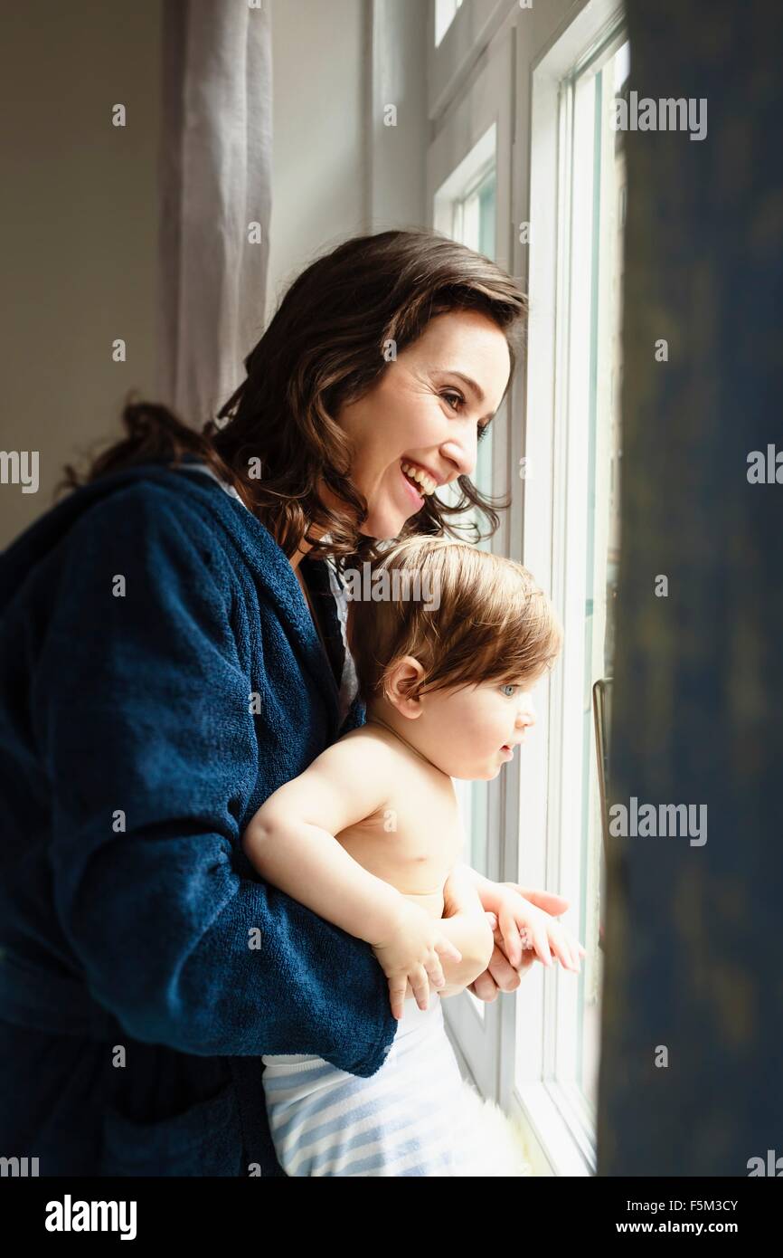 Mother and baby son looking through window Stock Photo