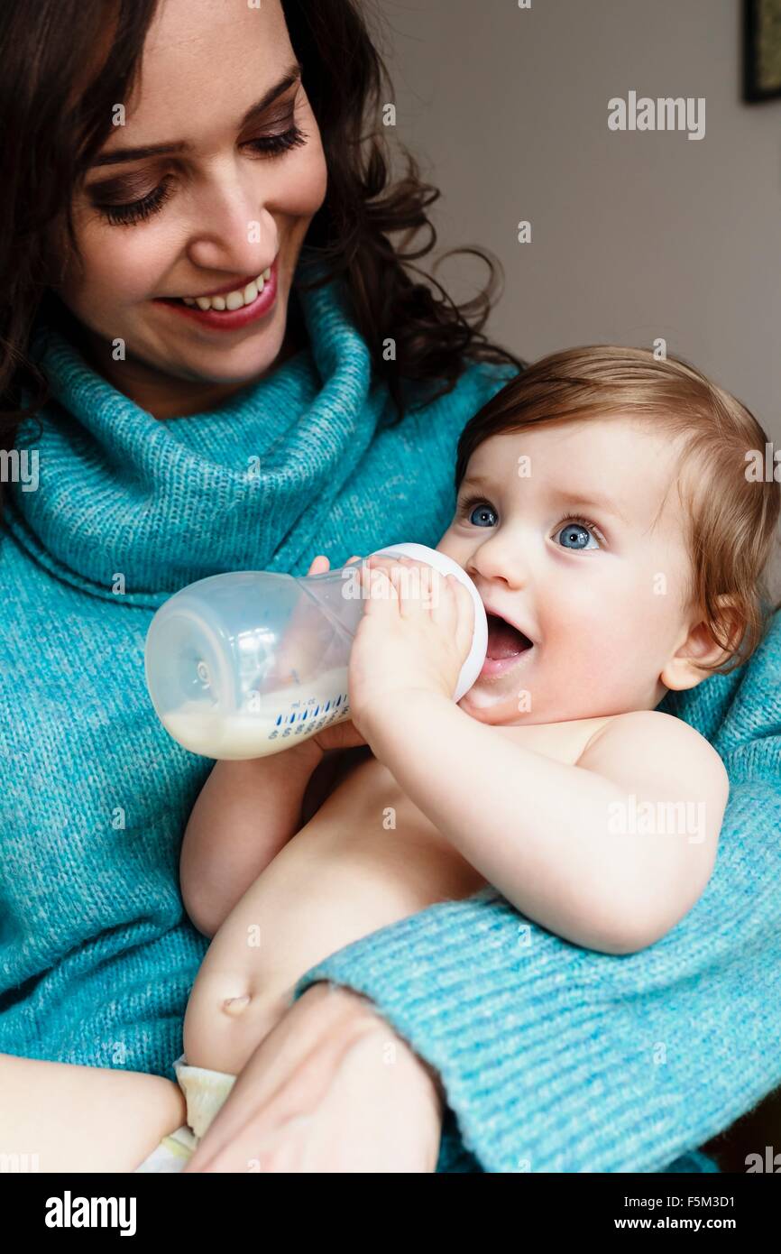 Mother watching baby boy drinking milk from bottle Stock Photo