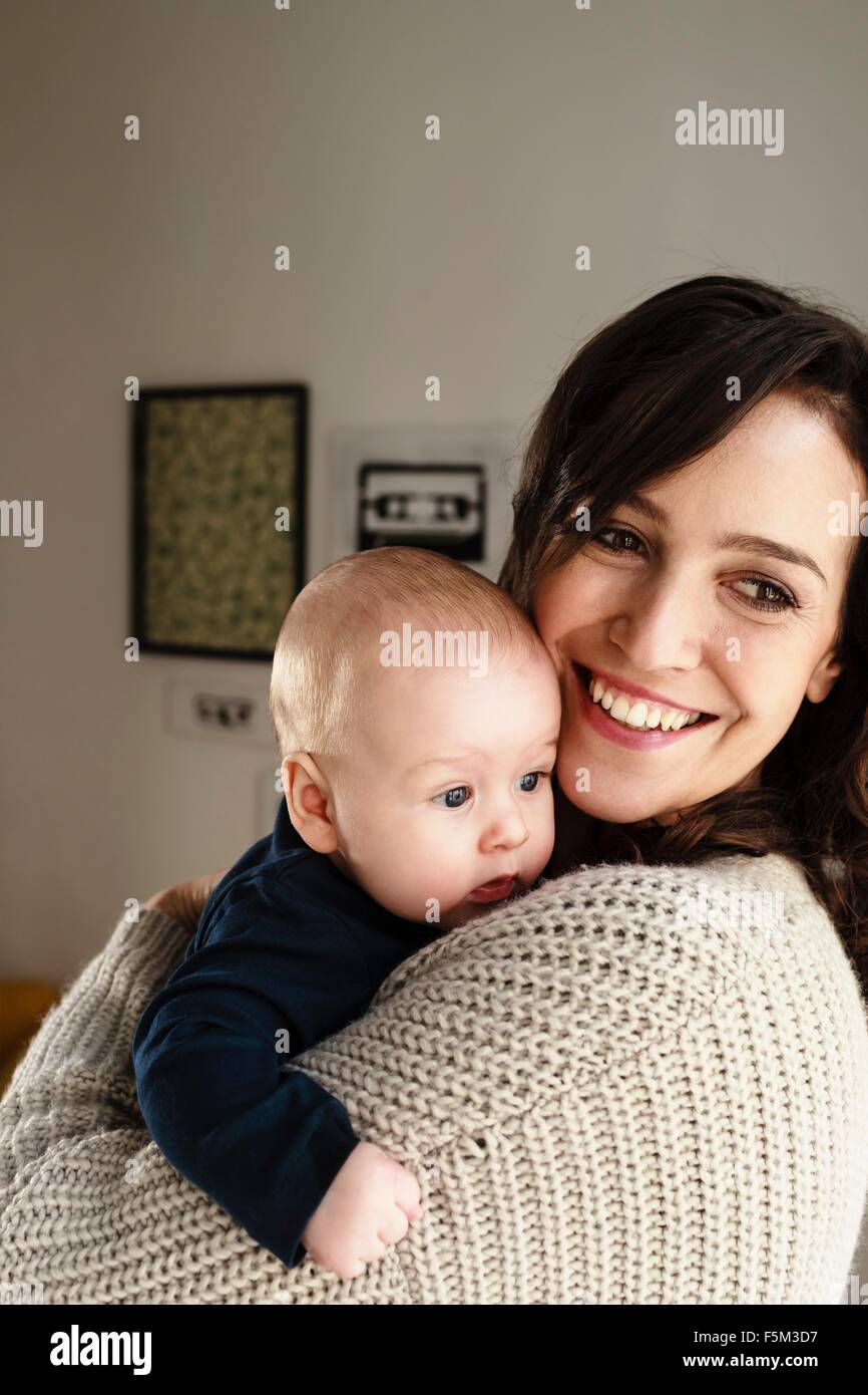 Mother holding baby son, looking over shoulder Stock Photo