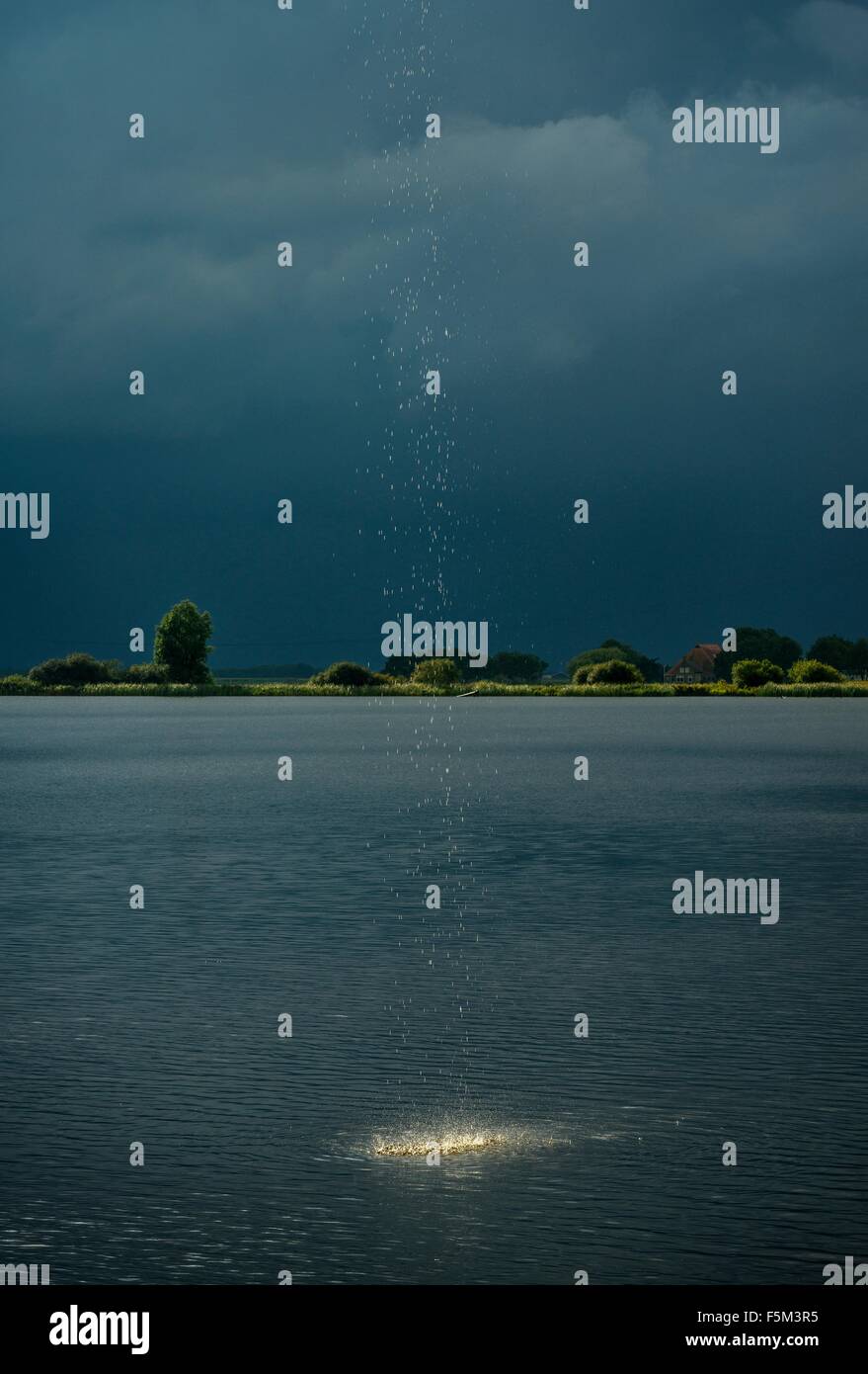 Heavy rainfall and droplets splashing into lake during thunderstorm Stock Photo