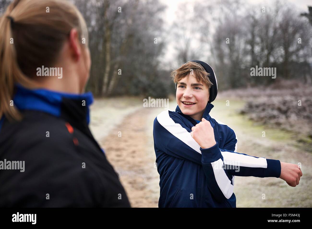 Teenage boy stretching arm, looking at mother smiling Stock Photo