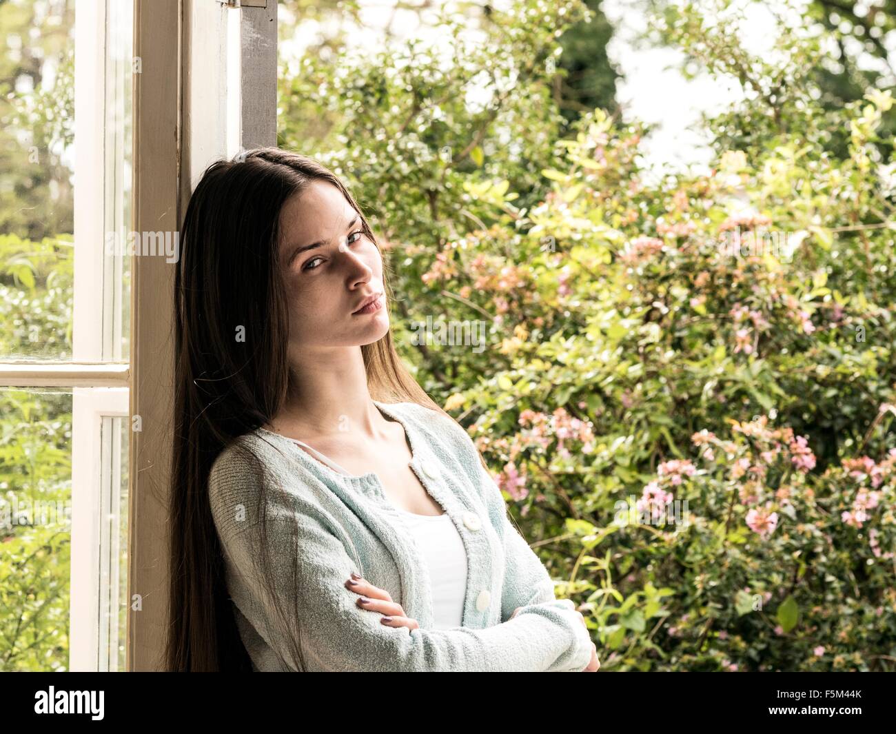 Portrait of young woman leaning against door frame Stock Photo - Alamy