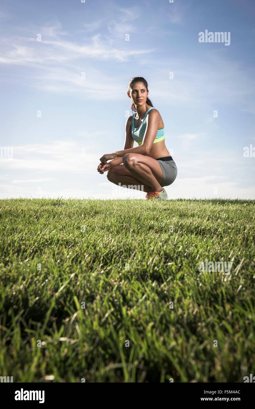 Portrait of confident athletic young woman crouching in park Stock Photo