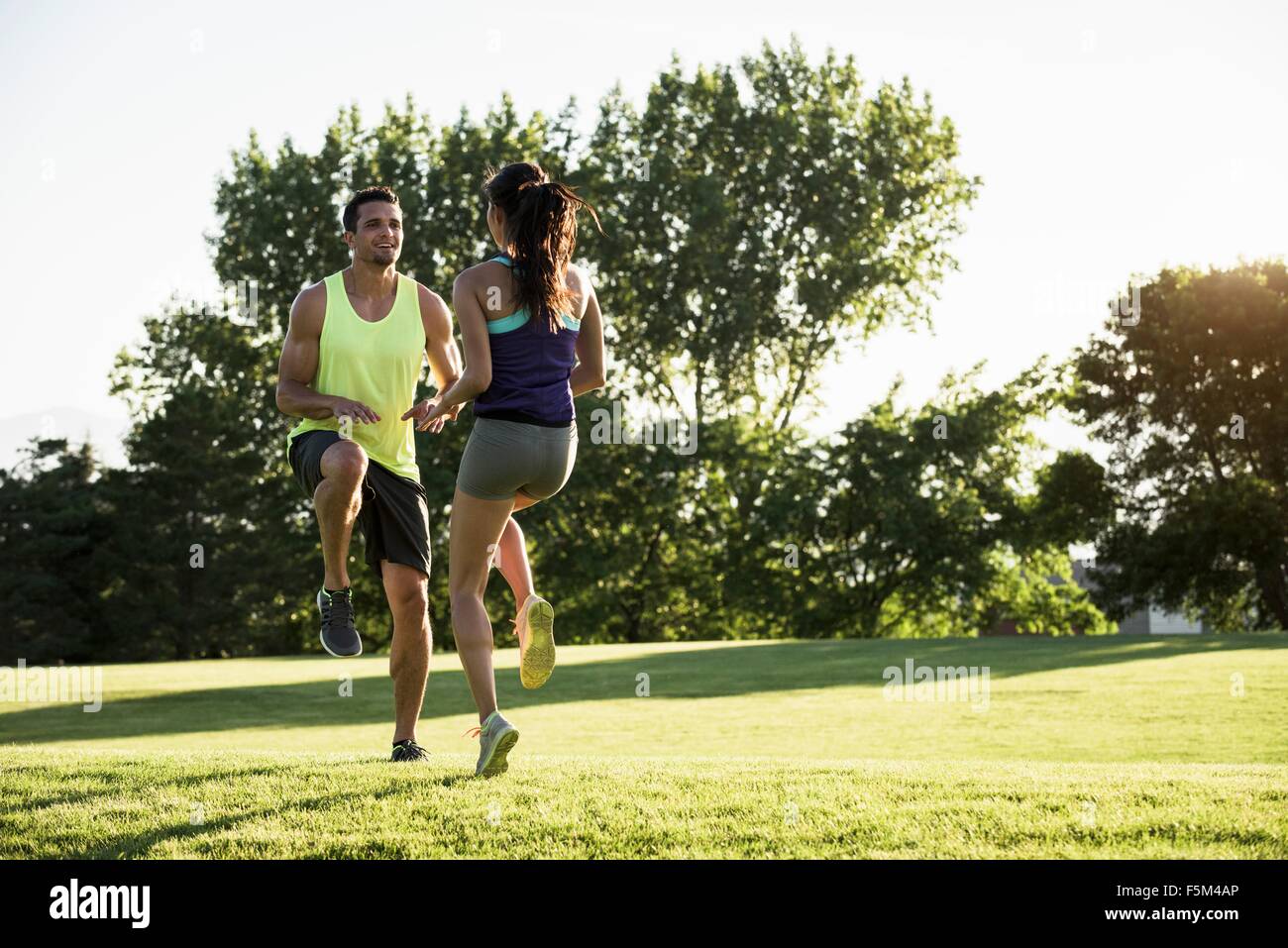 Young man and woman doing running on spot training in park Stock Photo