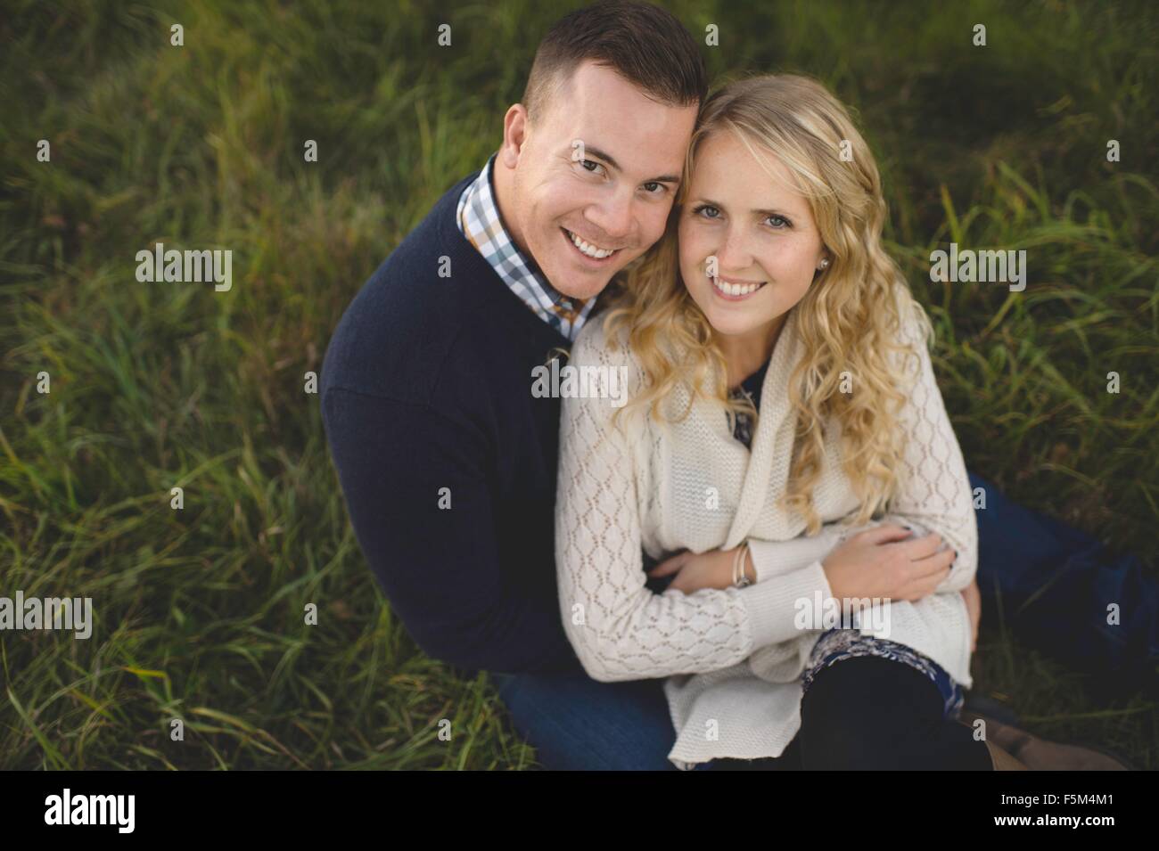 Portrait of mid adult couple sitting on grass Stock Photo