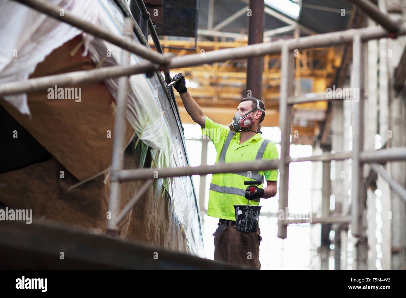 Worker on scaffold painting boat in shipyard Stock Photo Alamy