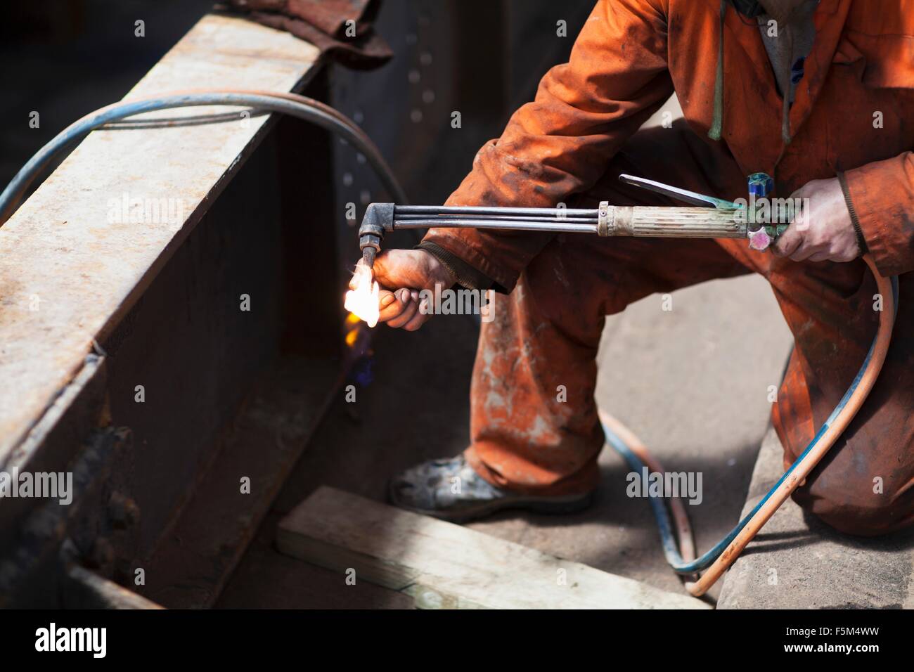 Welder lighting welding flame in shipyard workshop Stock Photo