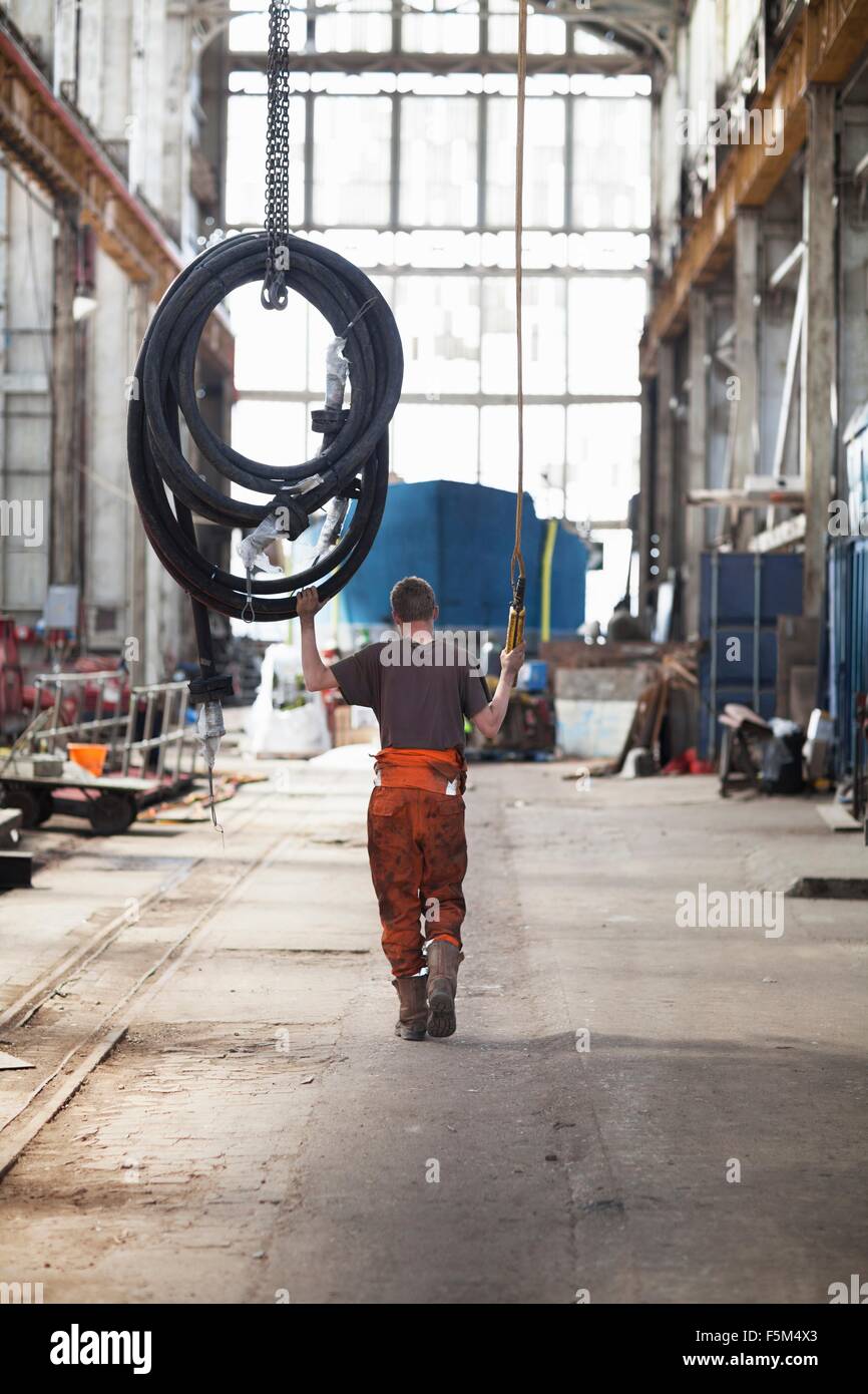 Pulling Works Rear view of worker pulling piping on winch in shipyard workshop Stock ...