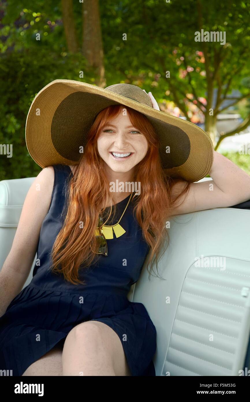 Portrait of young woman with long red hair in back seat of  vintage convertible Stock Photo
