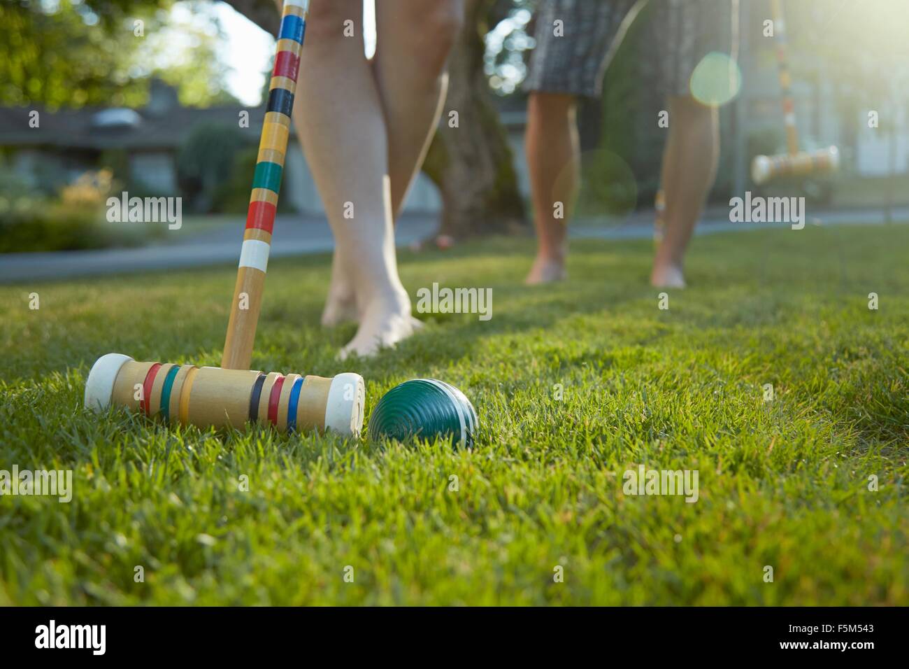 Legs and bare feet of young couple playing croquet on grass Stock Photo