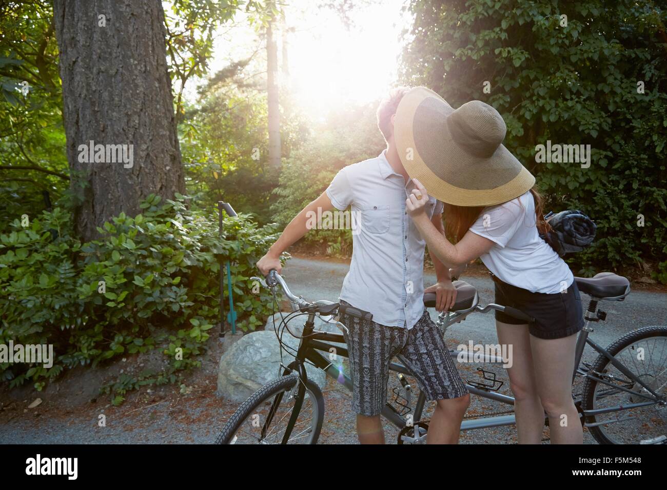 Young couple with tandem cycle kissing on rural road Stock Photo