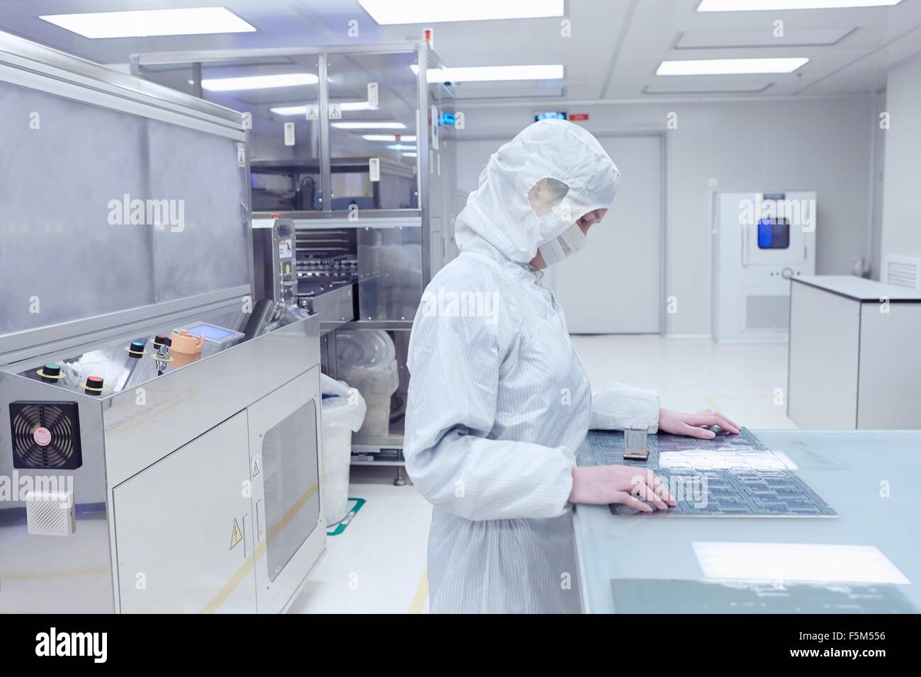 Female worker inspecting flex circuit in flexible electronics factory clean room Stock Photo