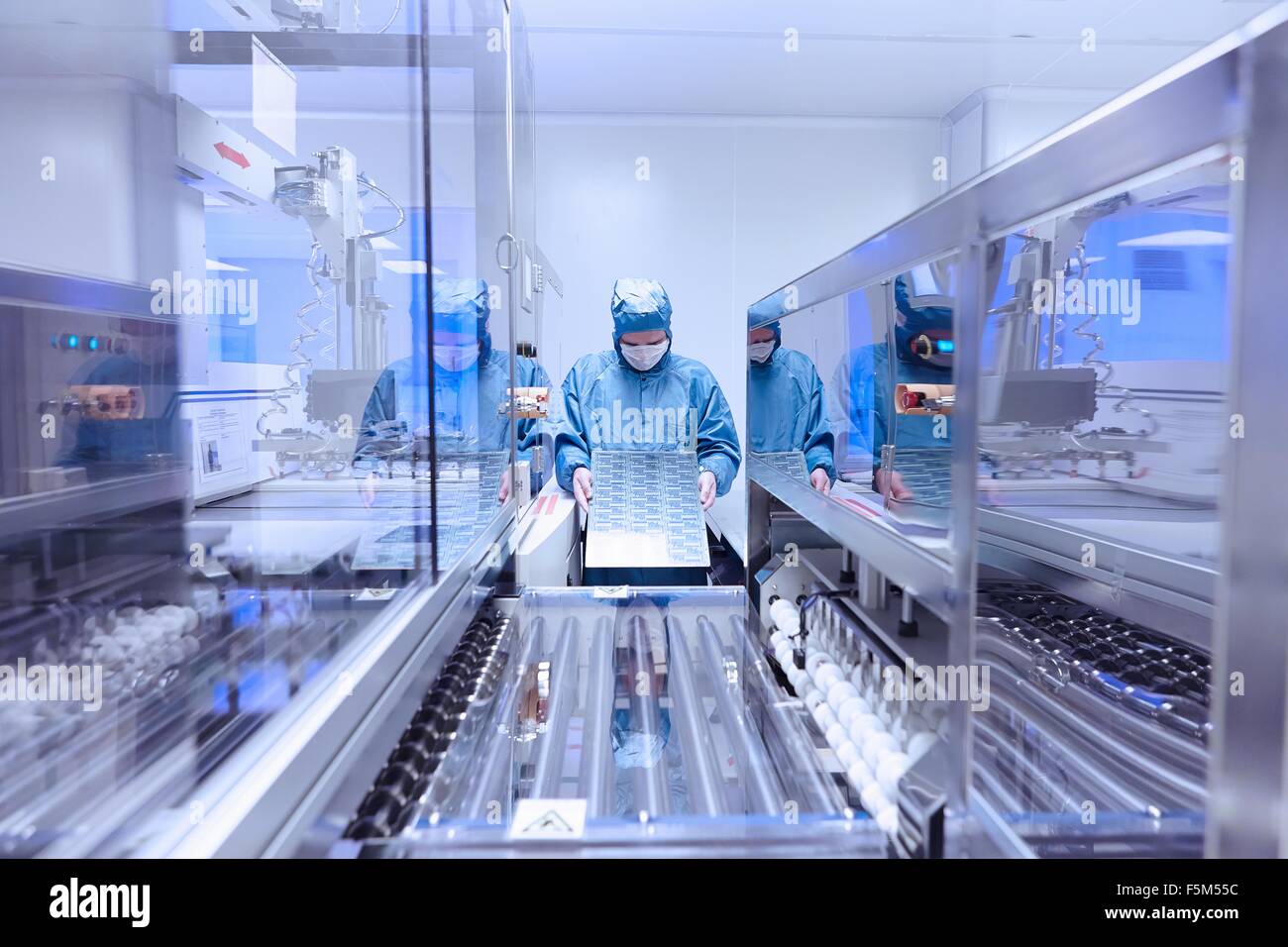 Male worker inspecting flex circuit in flexible electronics factory clean room Stock Photo
