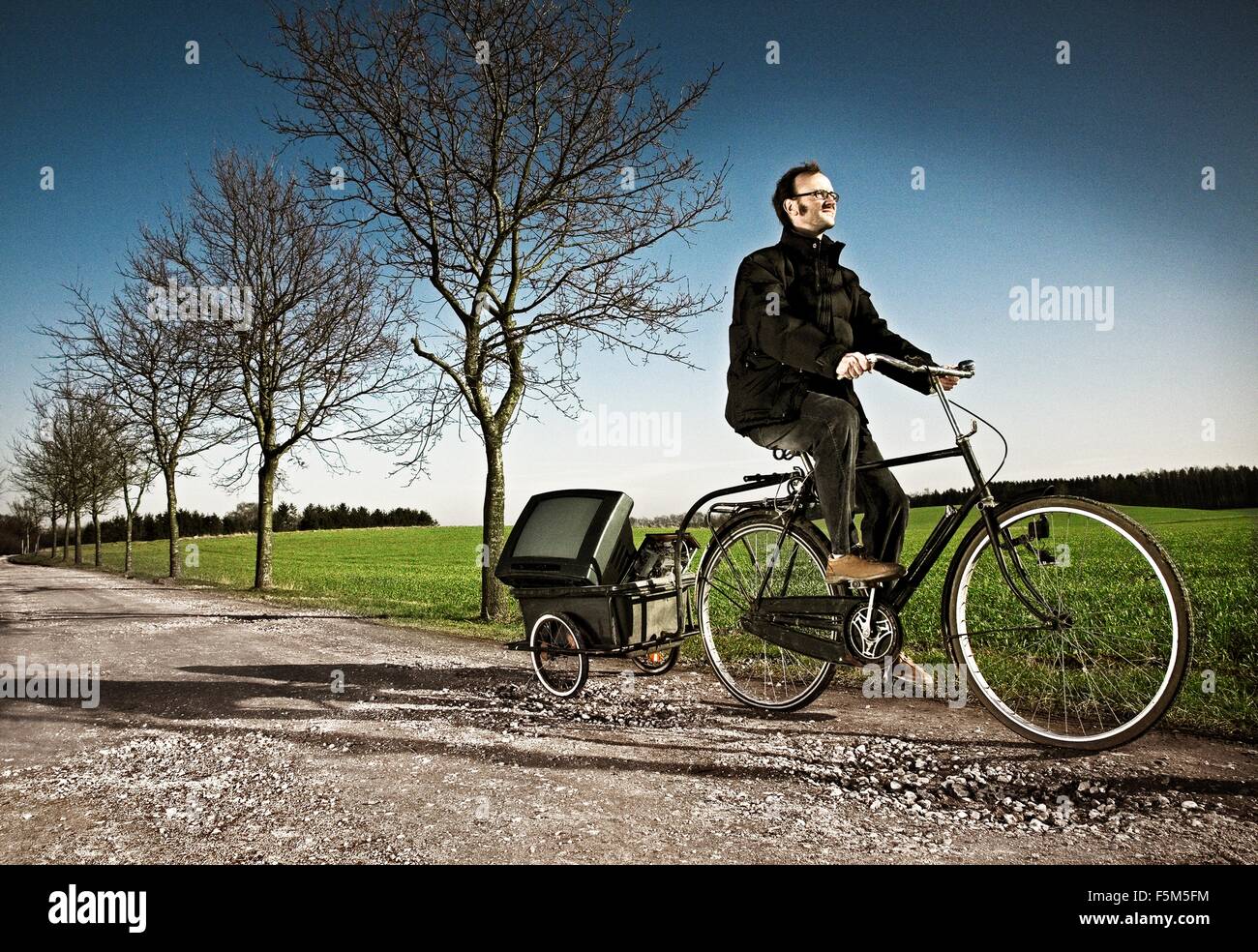 Man riding bicycle with carriage on country road, Ringsted, Denmark