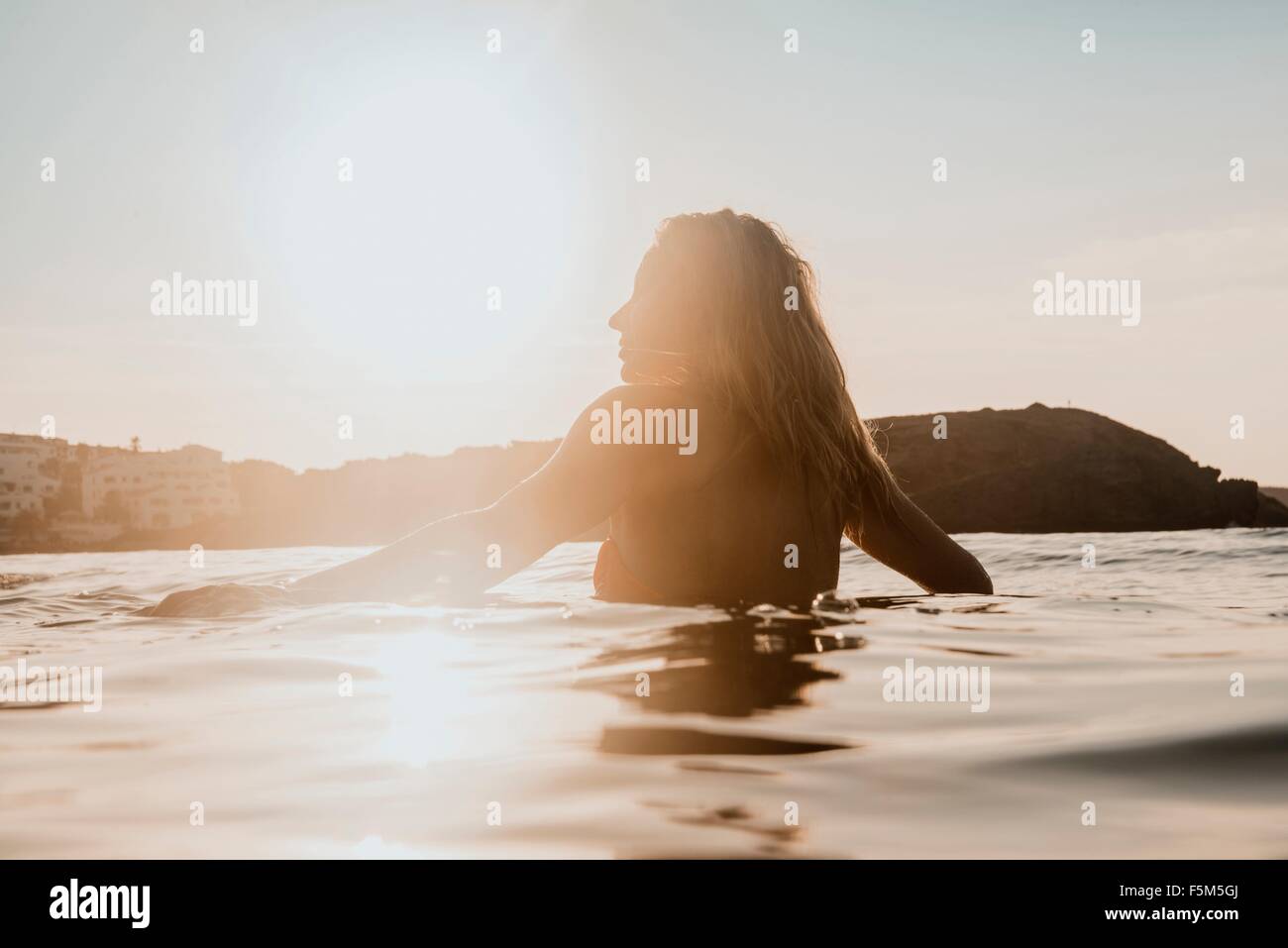 Silhouetted woman wading in sea at sunset, Menorca, Balearic islands, Spain Stock Photo