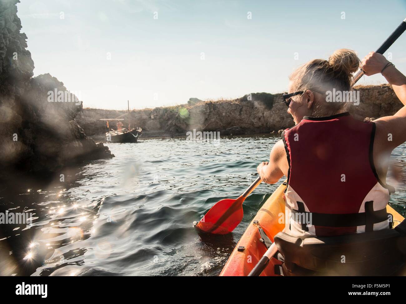 Rear view of woman sea kayaking, Menorca, Balearic islands, Spain Stock Photo