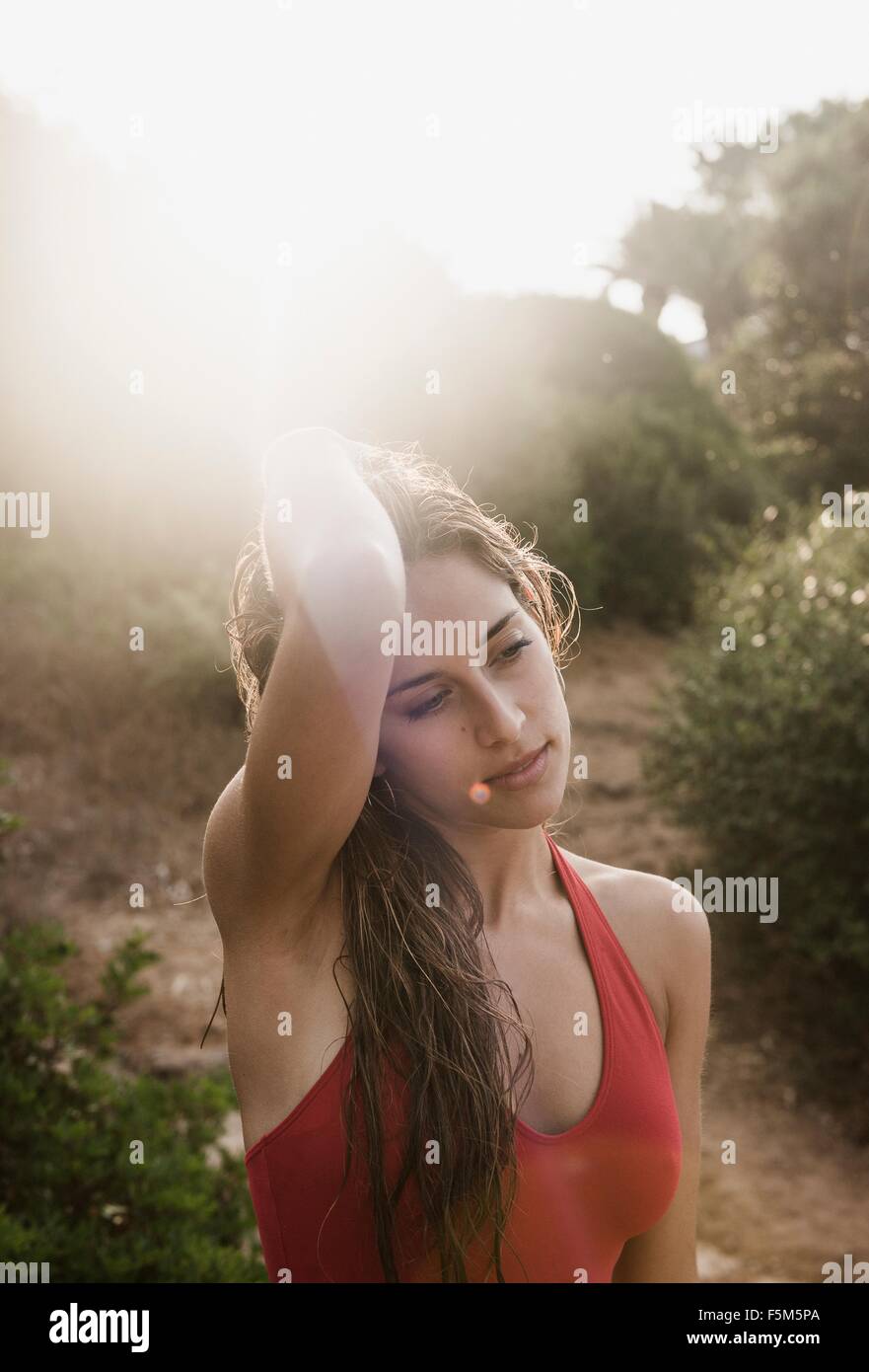 Portrait of sunlit young woman with hands in hair at beach Stock Photo