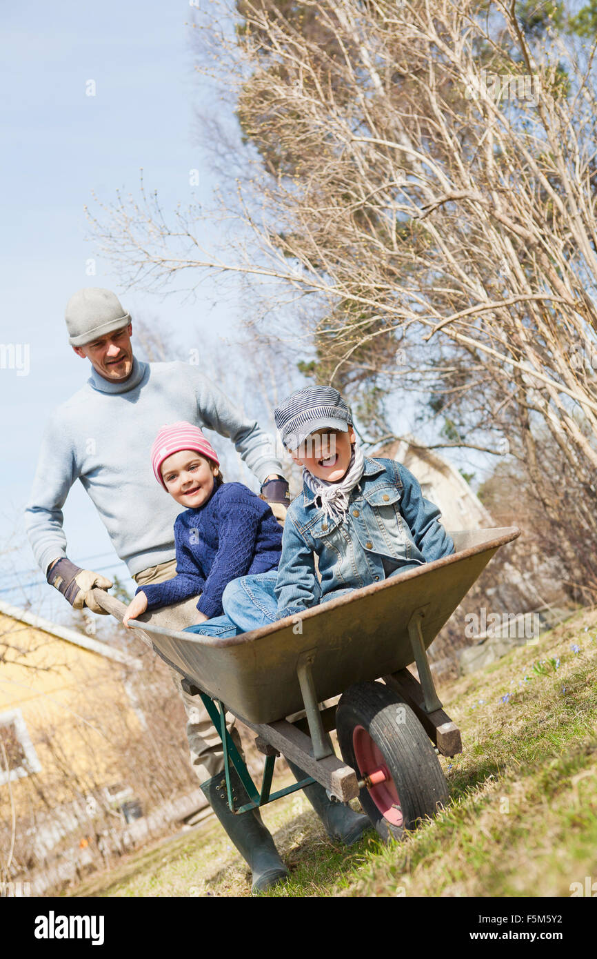 Sweden, Sodermanland, Huddinge, Stuvsta, Father with sons (4-5) in wheelbarrow Stock Photo