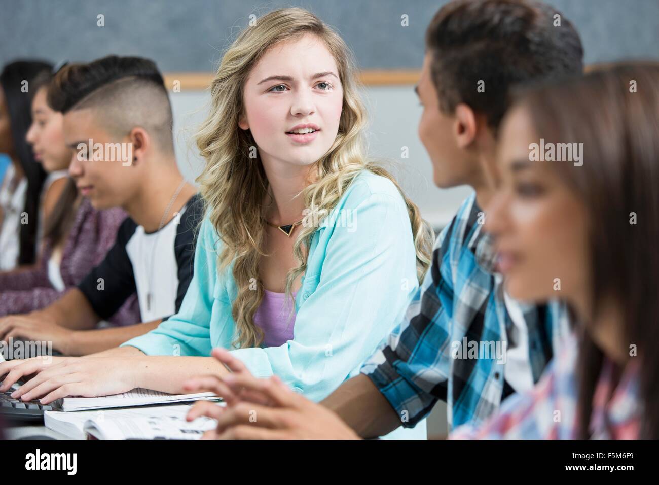Row of teenage high school students talking in computer class Stock Photo