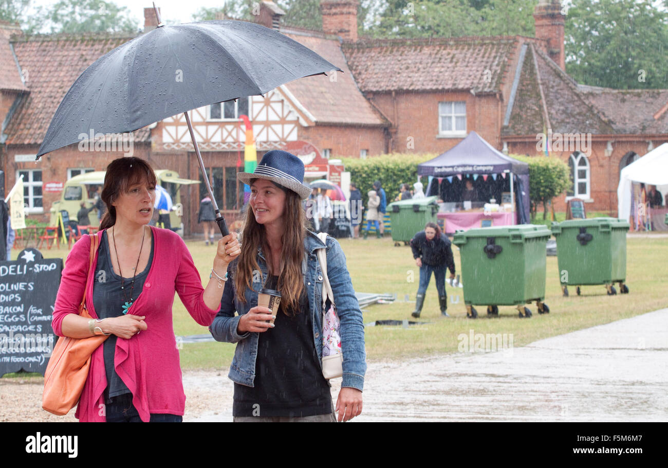 Two women under an umbrella at a rainy outdoor festival Stock Photo
