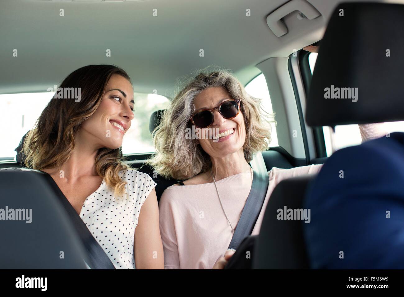 Two women chatting in back seat of car Stock Photo