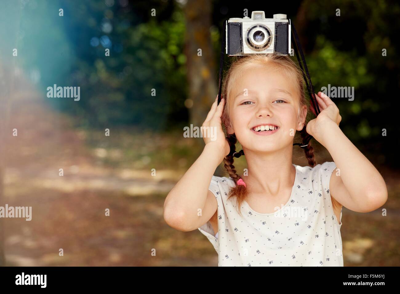 Girl with film camera on head looking at camera smiling Stock Photo - Alamy