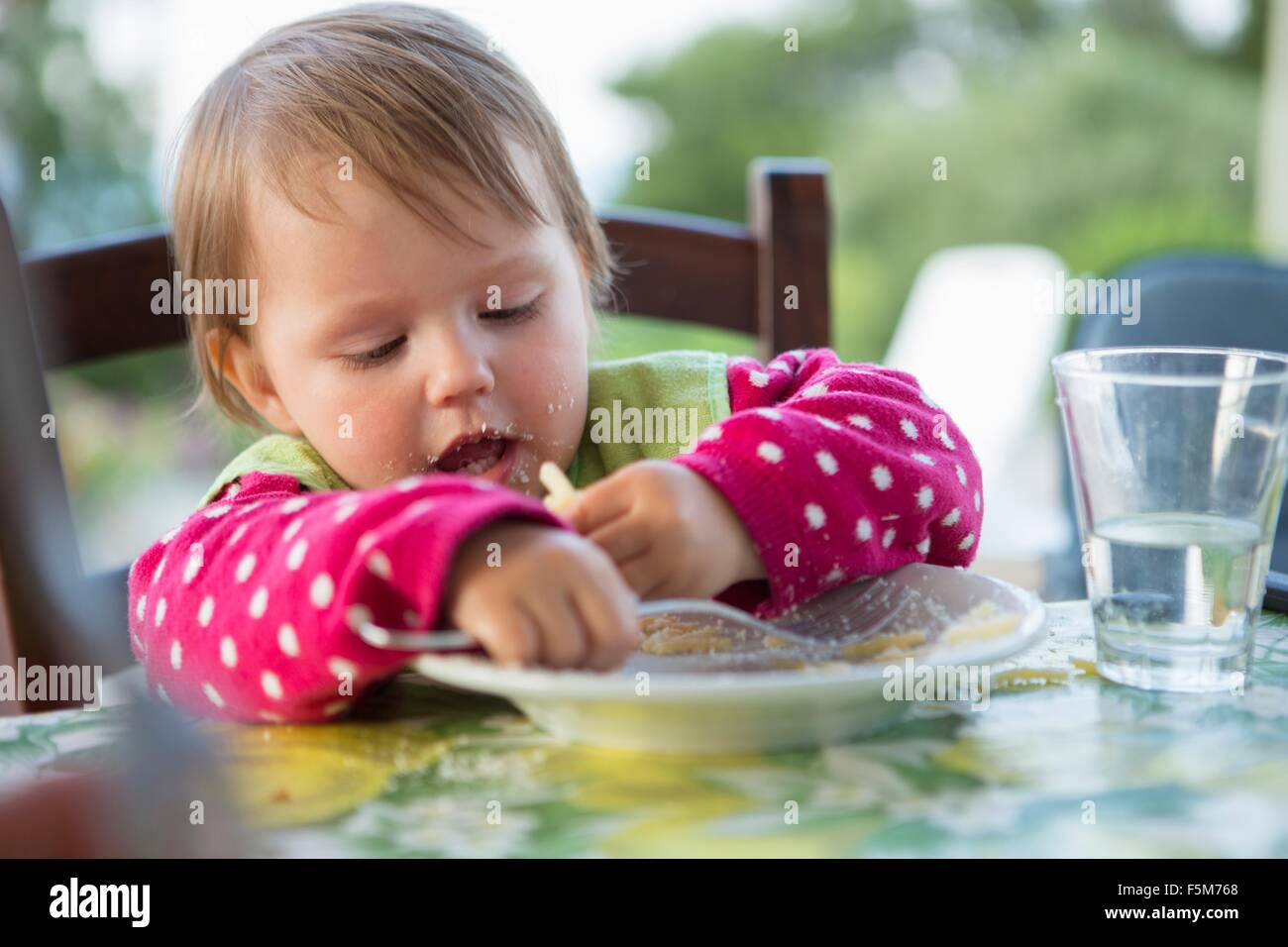 Female toddler eating at table Stock Photo