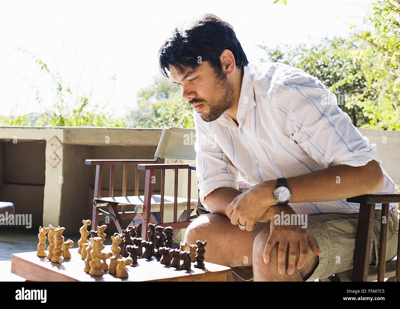 Mid adult man playing chess at safari lodge, Kafue National Park, Zambia Stock Photo