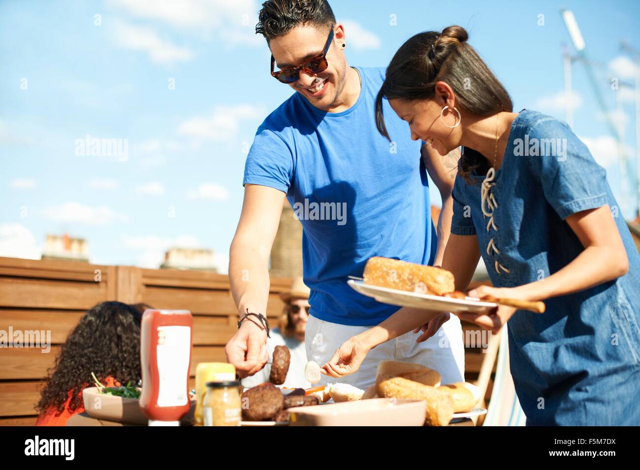 Mid adult woman selecting food at rooftop party Stock Photo