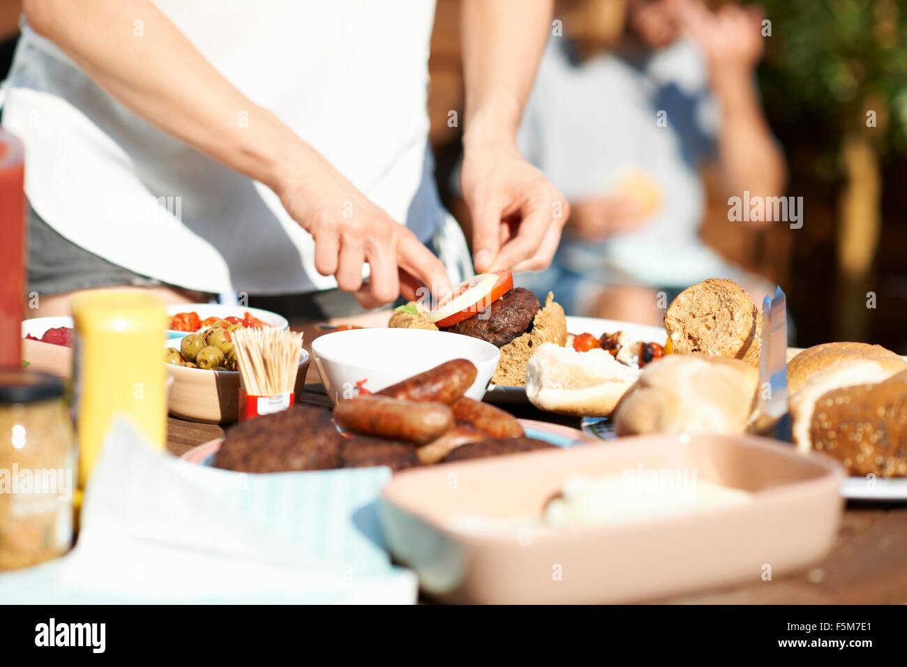 Cropped shot of male hands preparing burger at rooftop party Stock Photo
