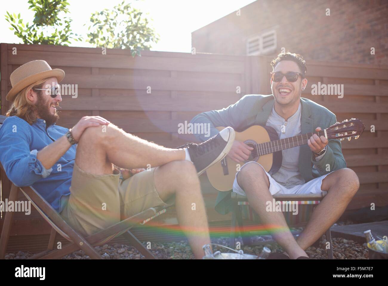 Two male friends playing guitar at rooftop party Stock Photo
