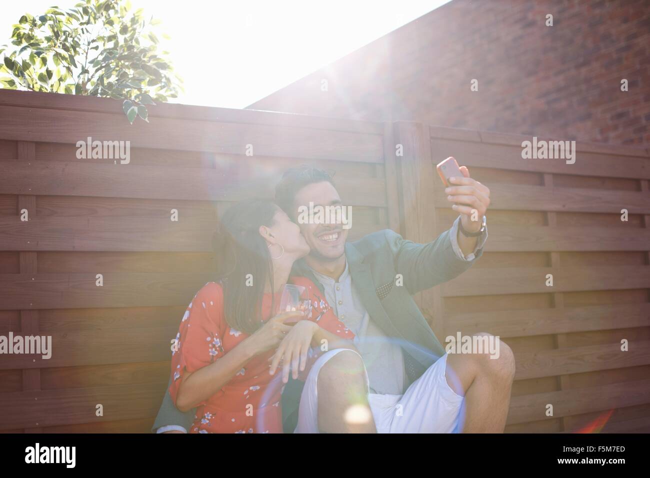 Mid adult couple taking smartphone selfie at rooftop party Stock Photo
