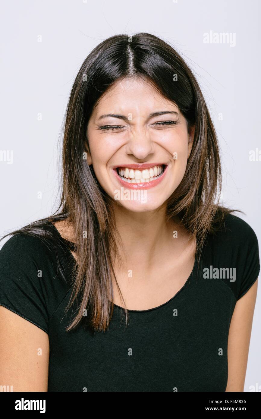 Head and shoulder portrait of young woman eyes closed toothy smile Stock Photo