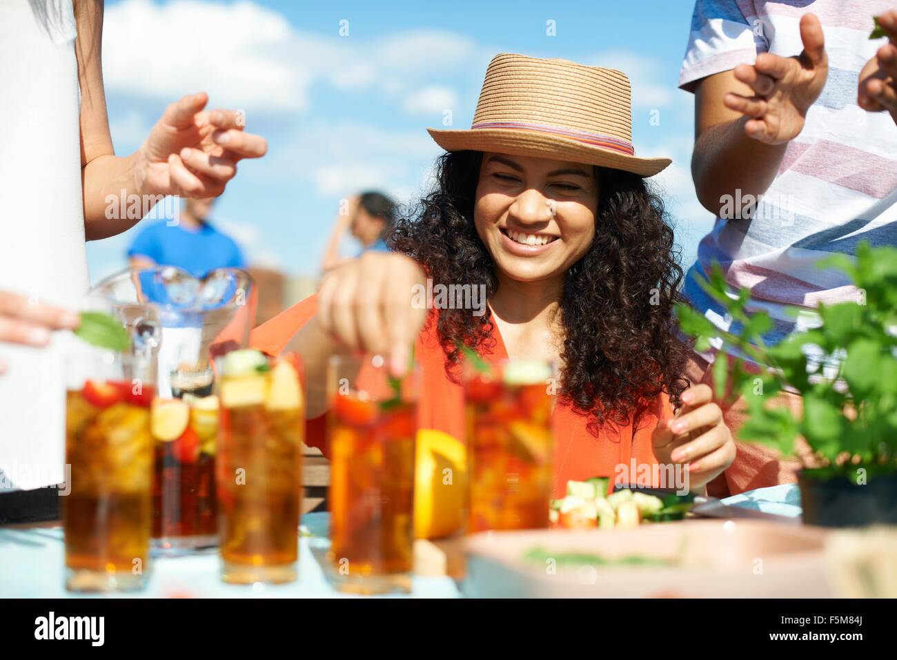Mid adult woman preparing cocktails at rooftop party Stock Photo