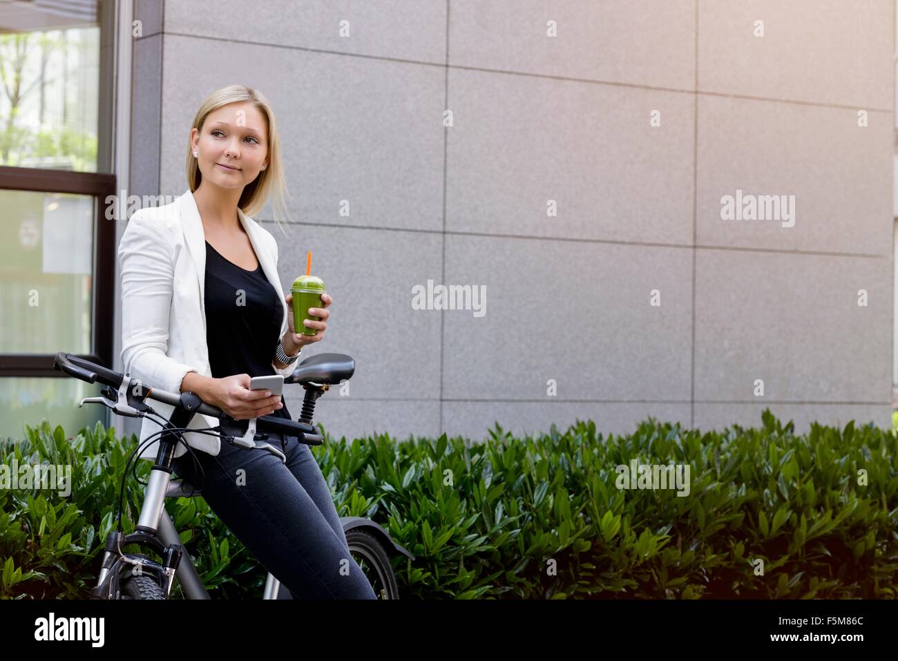 Young woman leaning against bicycle using smartphone Stock Photo
