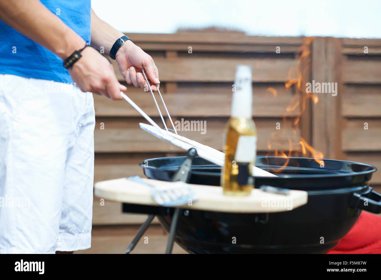 Cropped shot of mid adult man barbecuing at rooftop barbecue Stock Photo