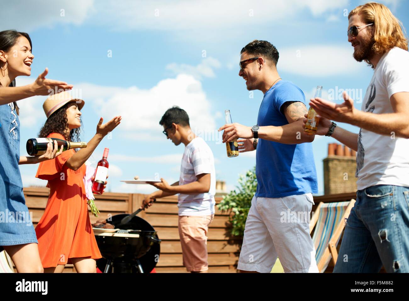 Female and male friends greeting at rooftop barbecue Stock Photo