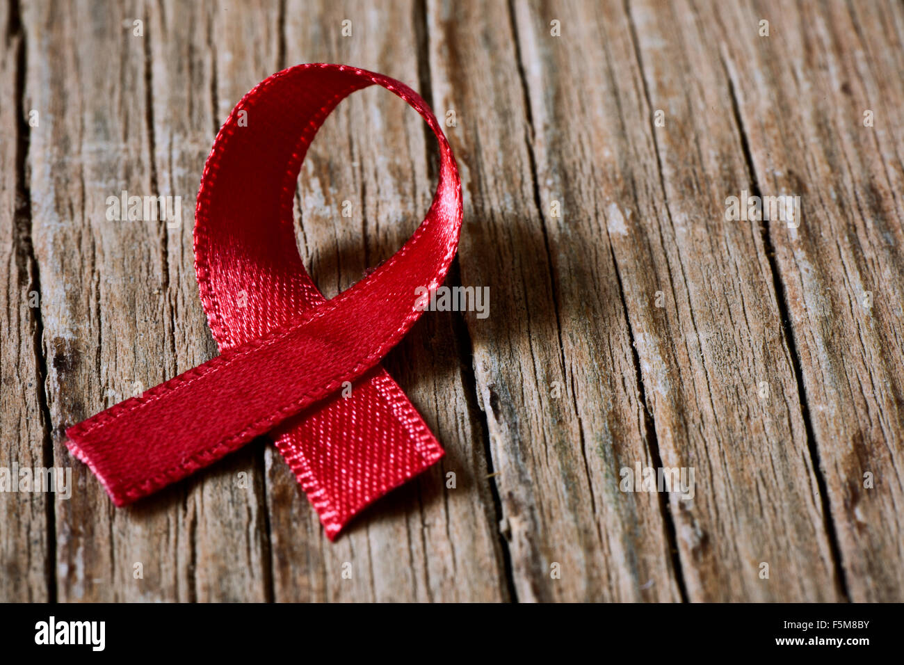 a red ribbon for the fight against AIDS on a rustic wooden surface Stock Photo