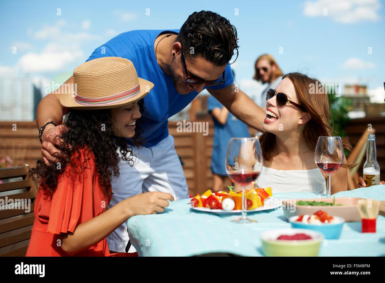 Male and female friends chatting at rooftop barbecue Stock Photo
