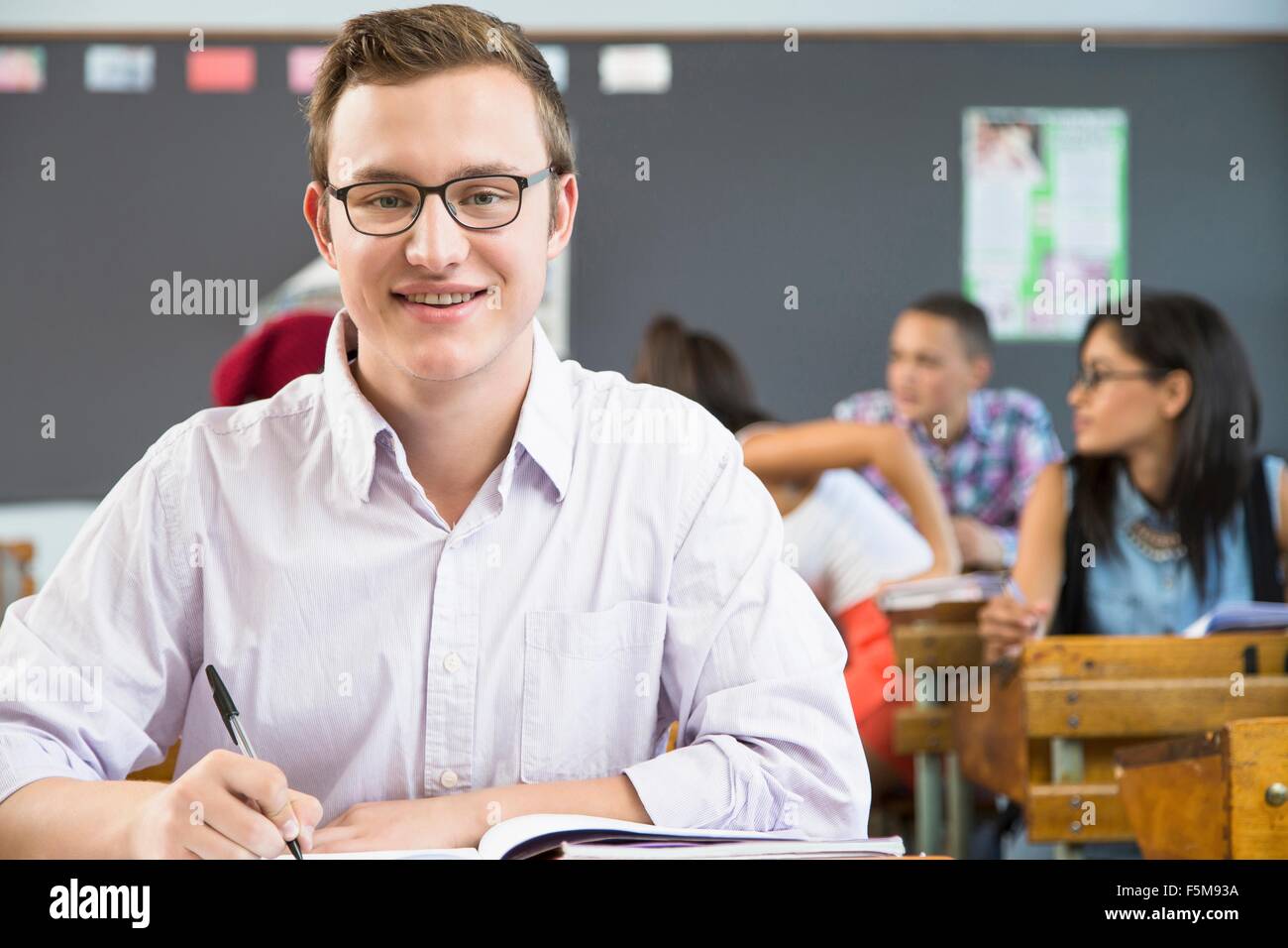 Portrait of male student, sitting at desk in classroom Stock Photo - Alamy