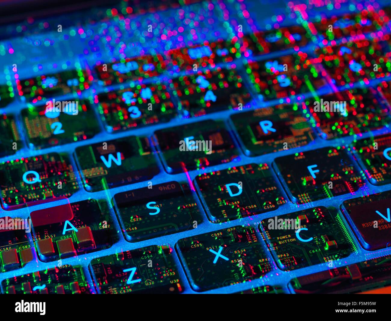 Double exposure of the inside and out of a laptop computer showing the electronic components under the keyboard Stock Photo