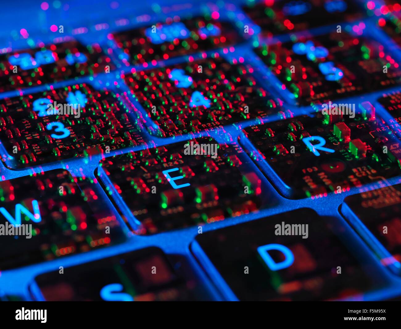 Double exposure of the inside and out of a laptop computer showing the electronic components under the keyboard Stock Photo