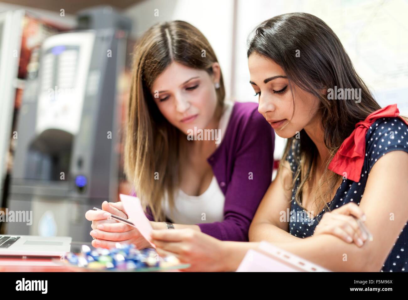 Two young women sitting together, studying Stock Photo